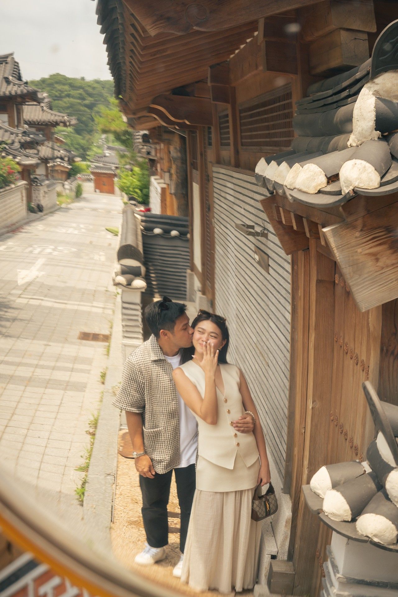 People in traditional Korean hanbok clothing walking along a stone path near traditional wooden buildings.