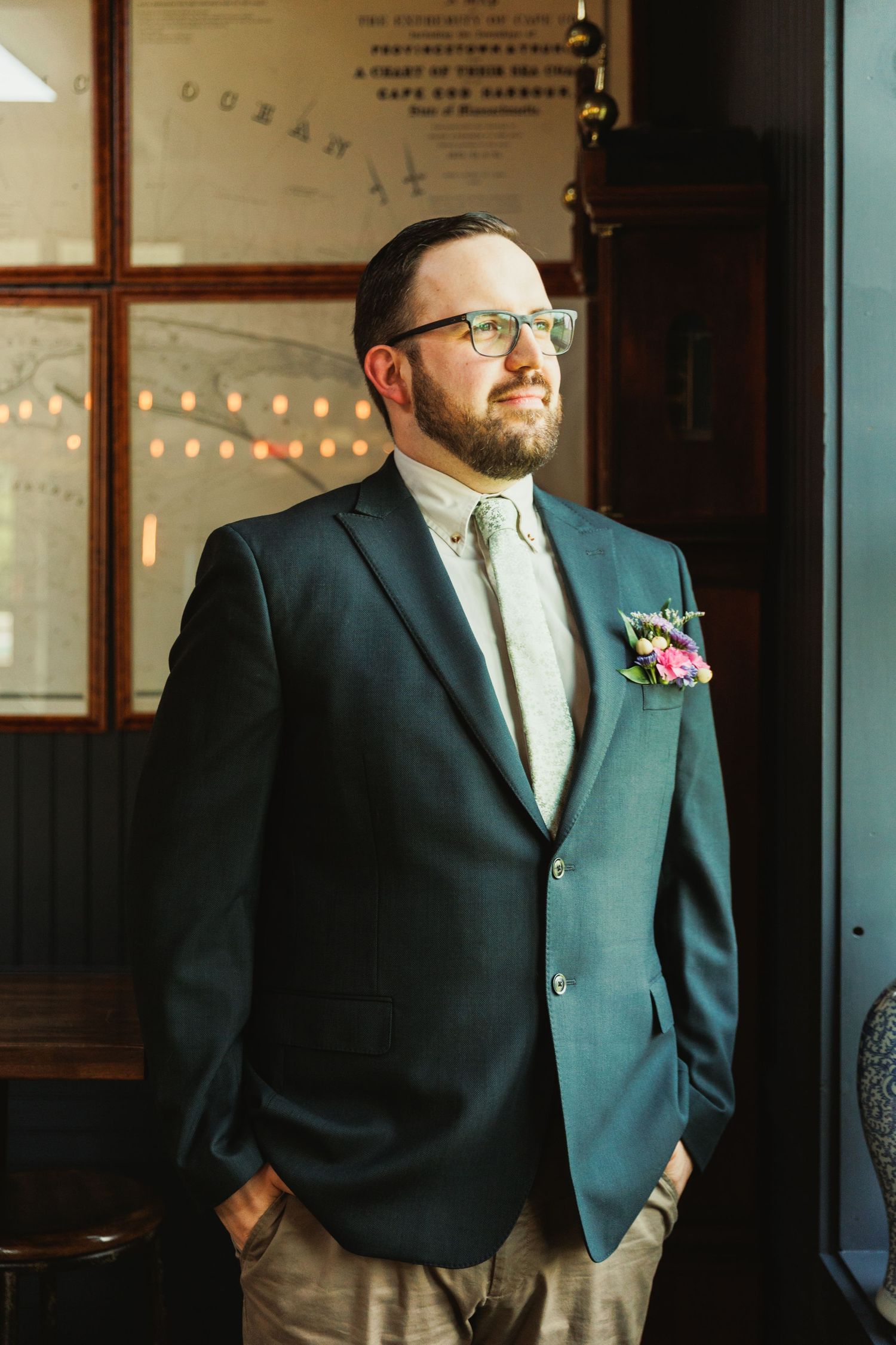 Natural window light illuminates formal attire against rustic interior with string lights.
