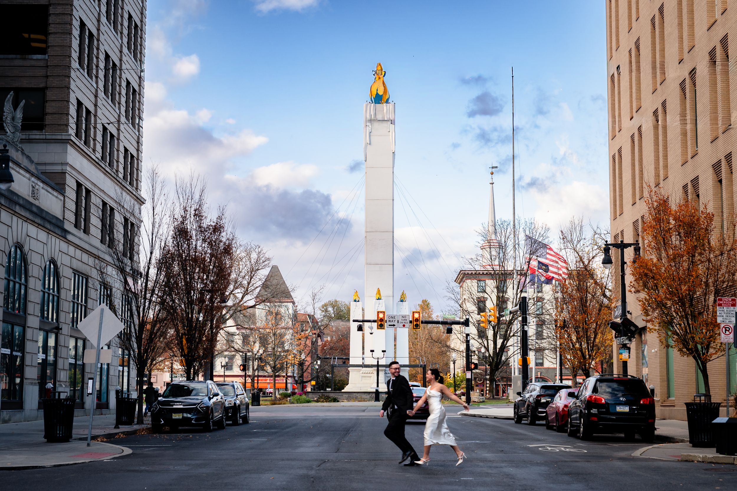A pedestrian crosses a street in downtown Worcester, Massachusetts with City Hall's iconic tower rising in the background.