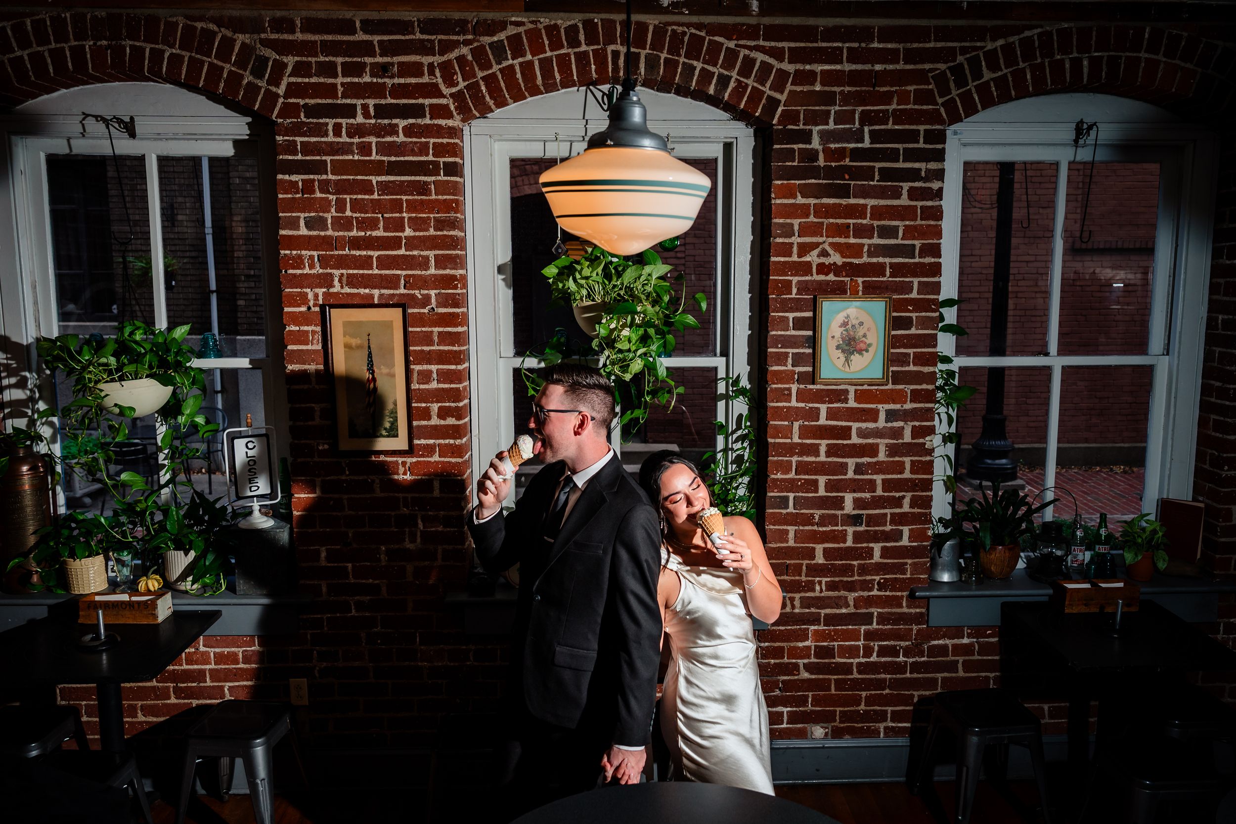 A romantic scene unfolds against a rustic brick wall backdrop with moody lighting and warm glowing orbs.