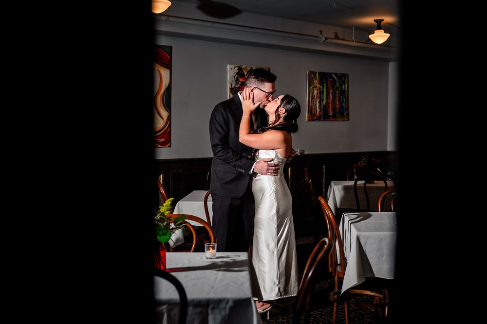 Romantic couple shares an intimate moment in a dimly lit venue with ambient lighting.
