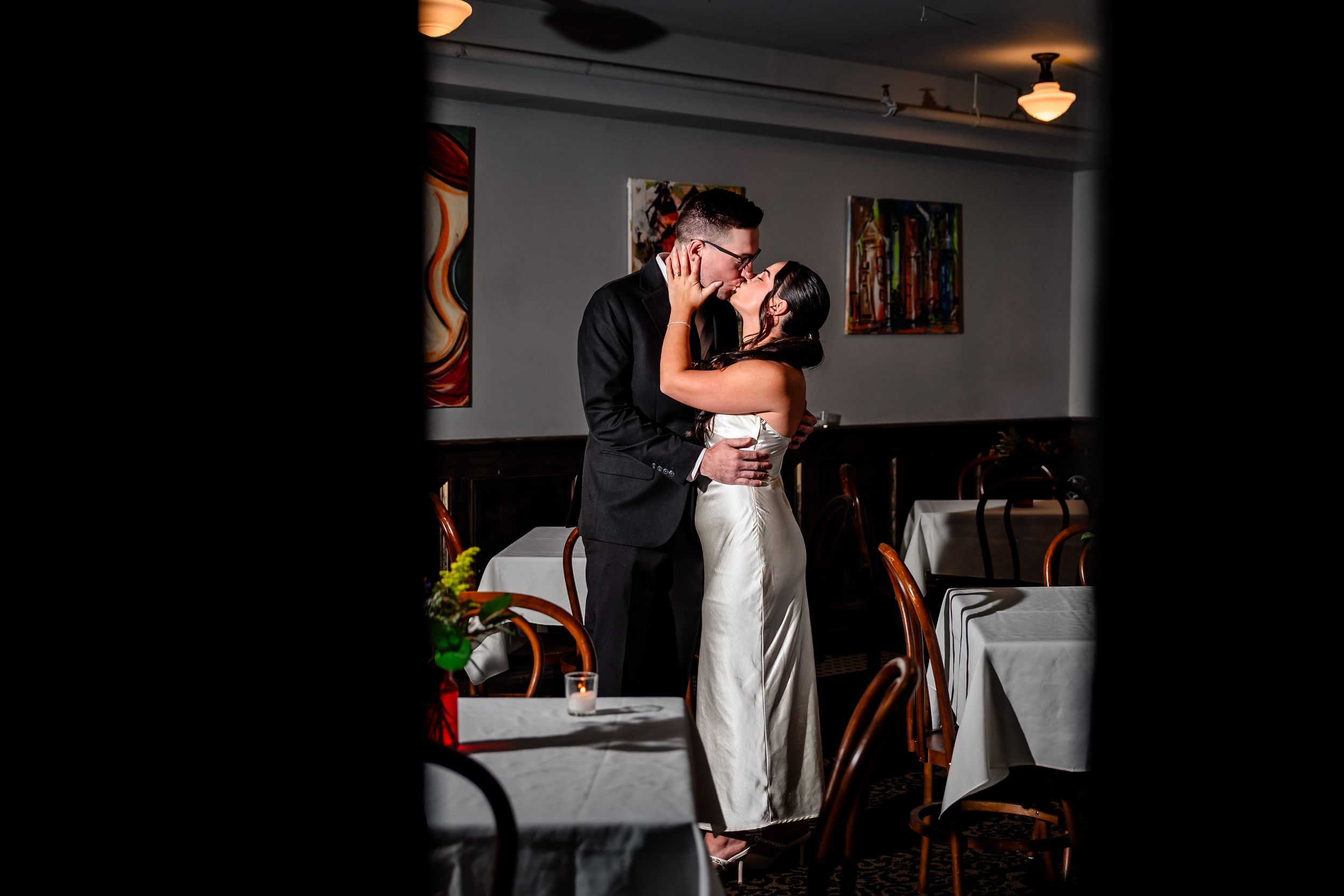 Romantic couple shares an intimate moment in a dimly lit venue with ambient lighting.