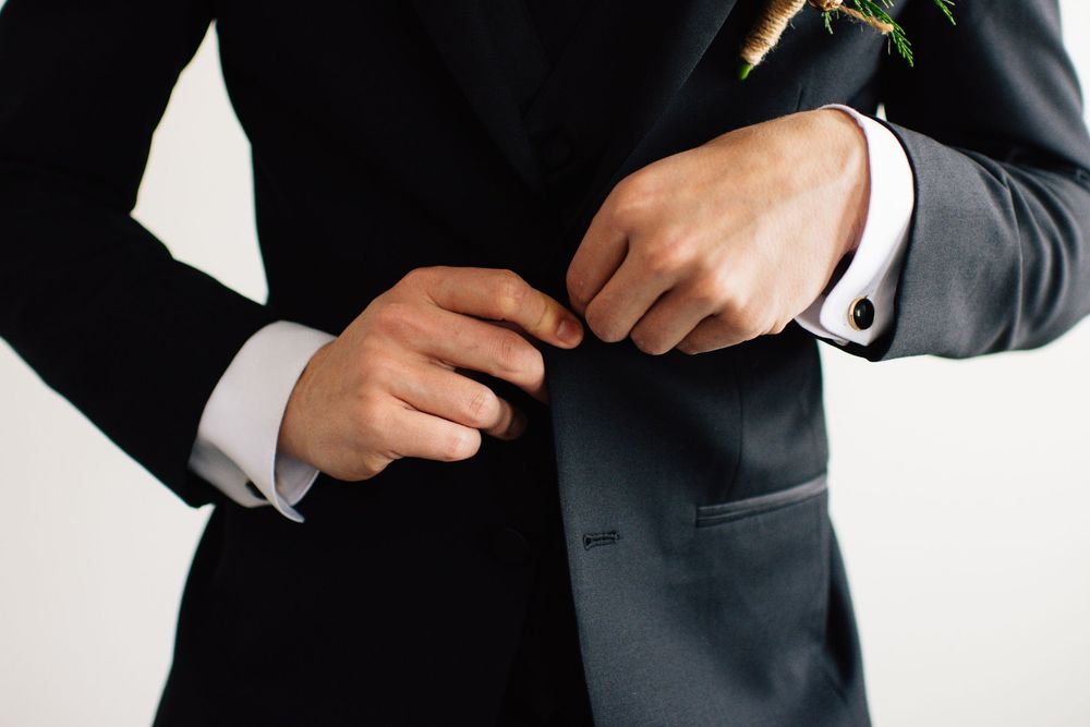 Close-up shots of hands adjusting formal black suit and accessories.
