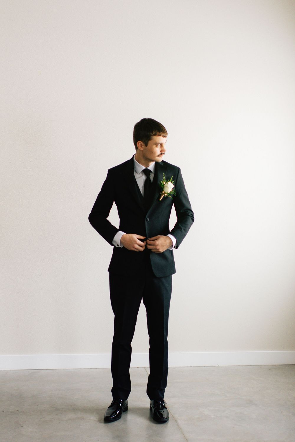 Person in black suit and tie posing dynamically against white studio background.