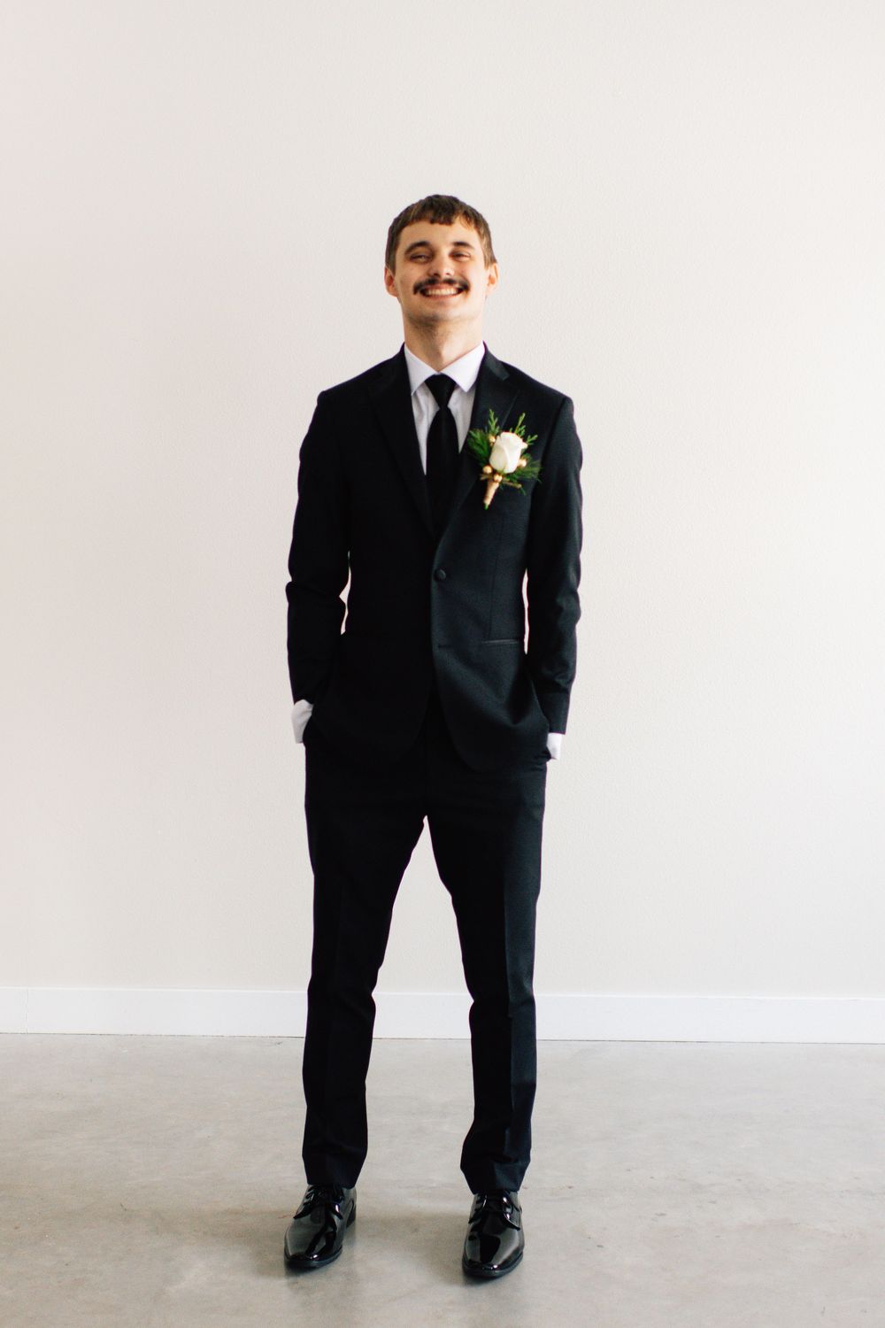 Person in formal black suit standing against white background in various poses.