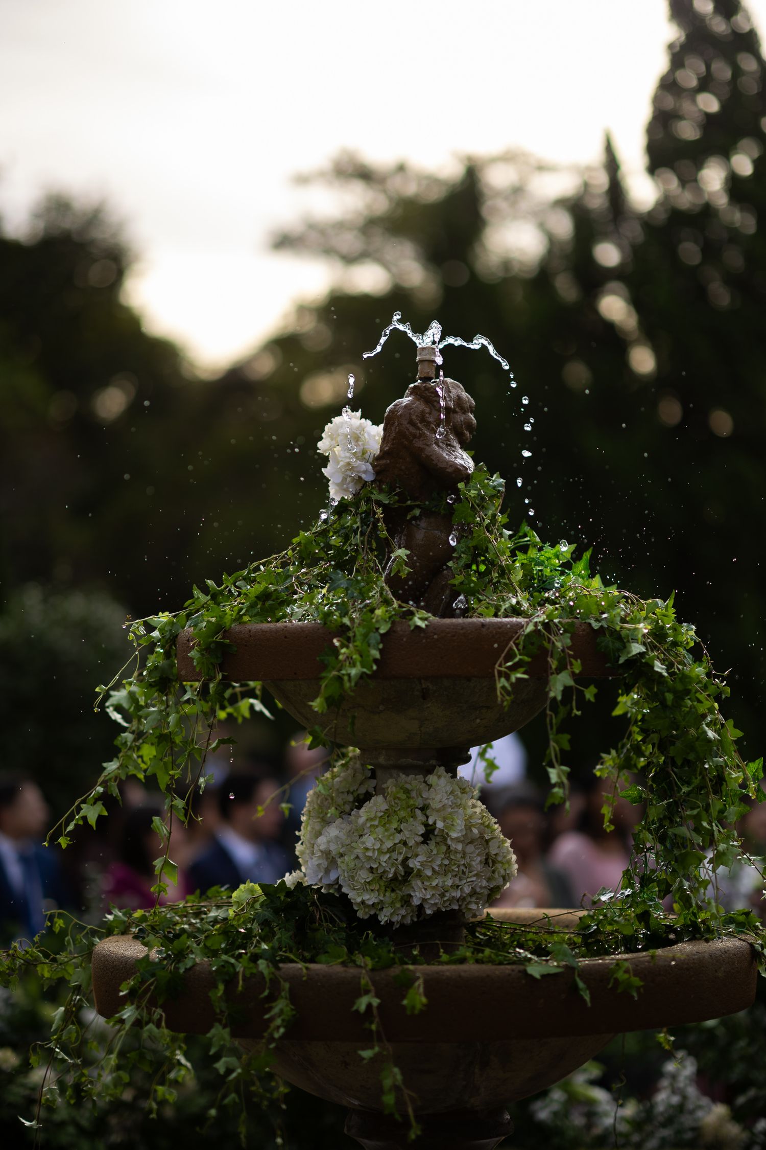 Decorative garden tiers with cascading greenery and white flowers arranged against a dusky evening sky.