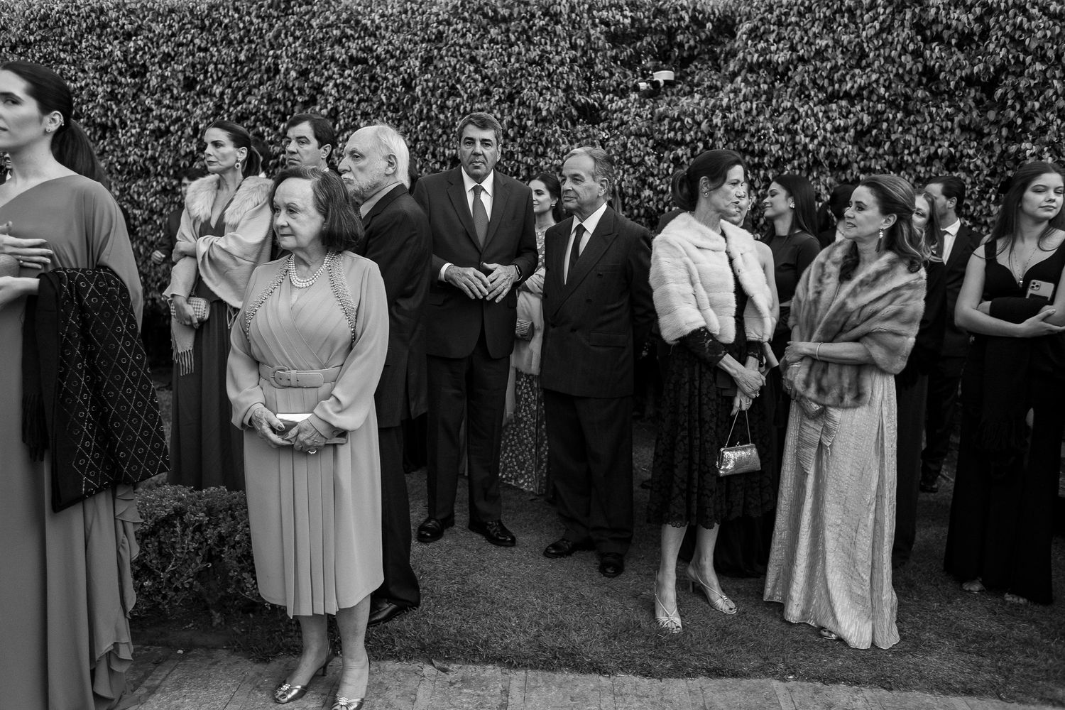 Wedding guests gathered in a garden setting share joyful moments during an outdoor celebration.