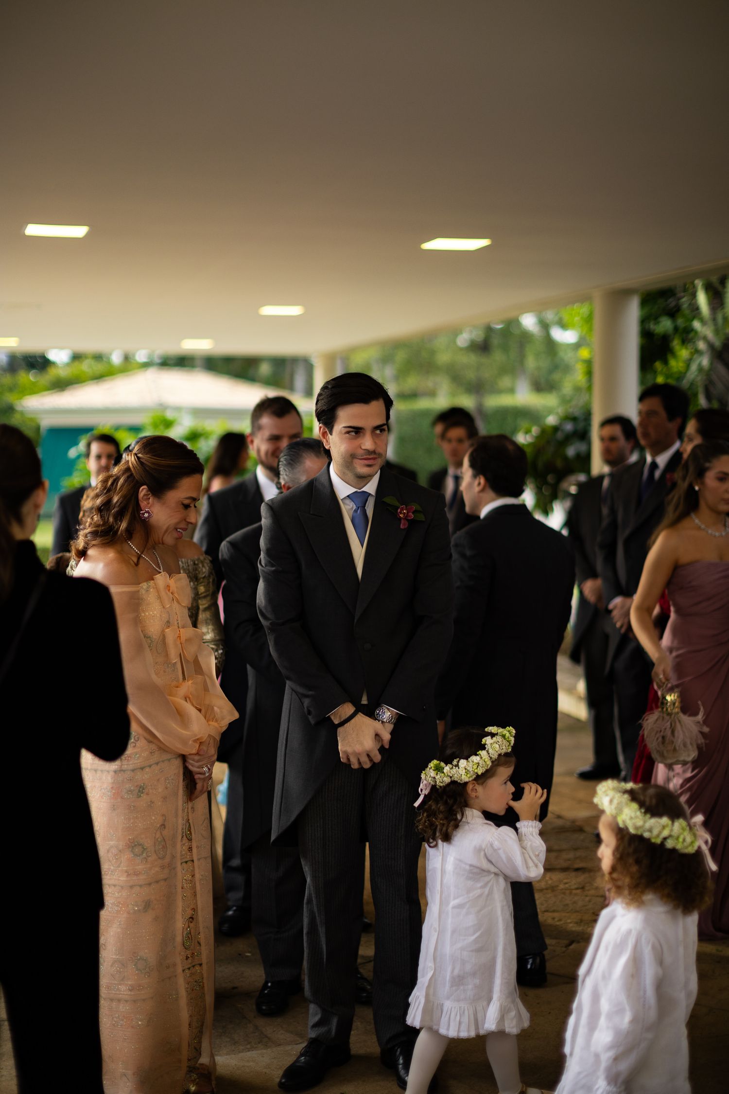 Wedding guests in formal attire gather at an elegant covered outdoor venue during a reception.