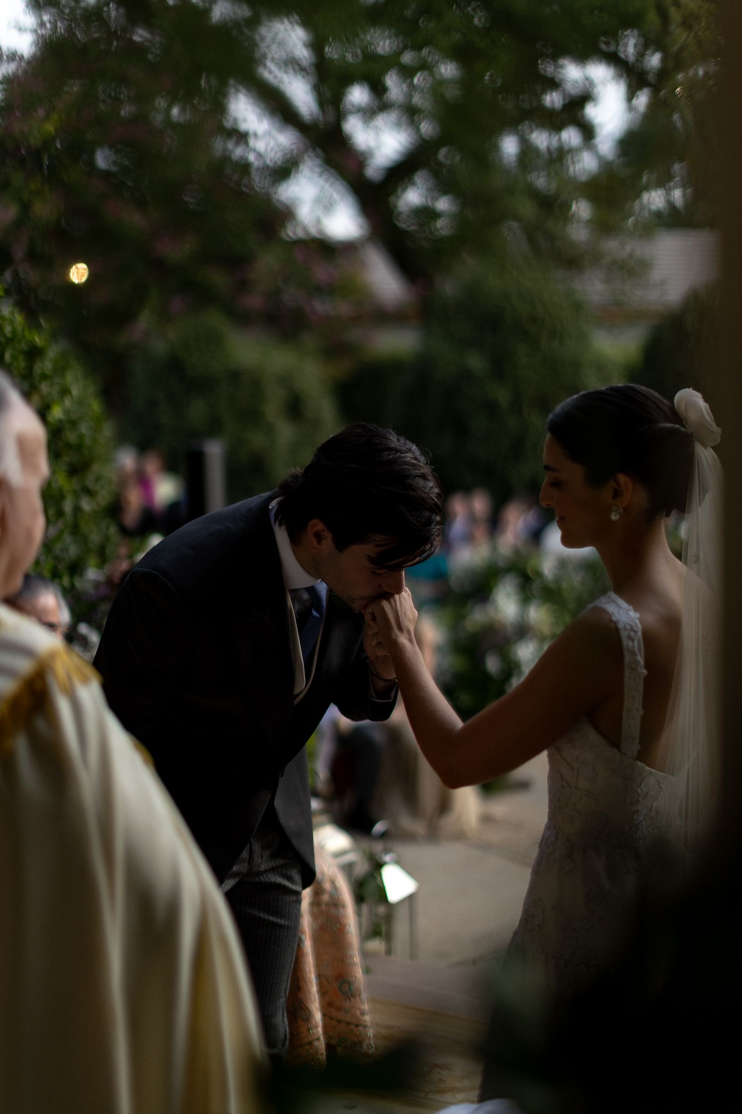 A couple embraces in a romantic silhouette against a soft outdoor background during a wedding ceremony.