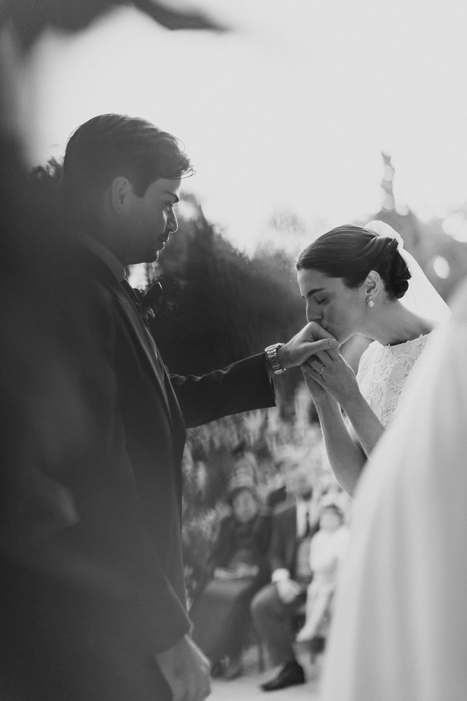 A tender black and white wedding moment captured during the ceremony as the couple shares an intimate gesture.