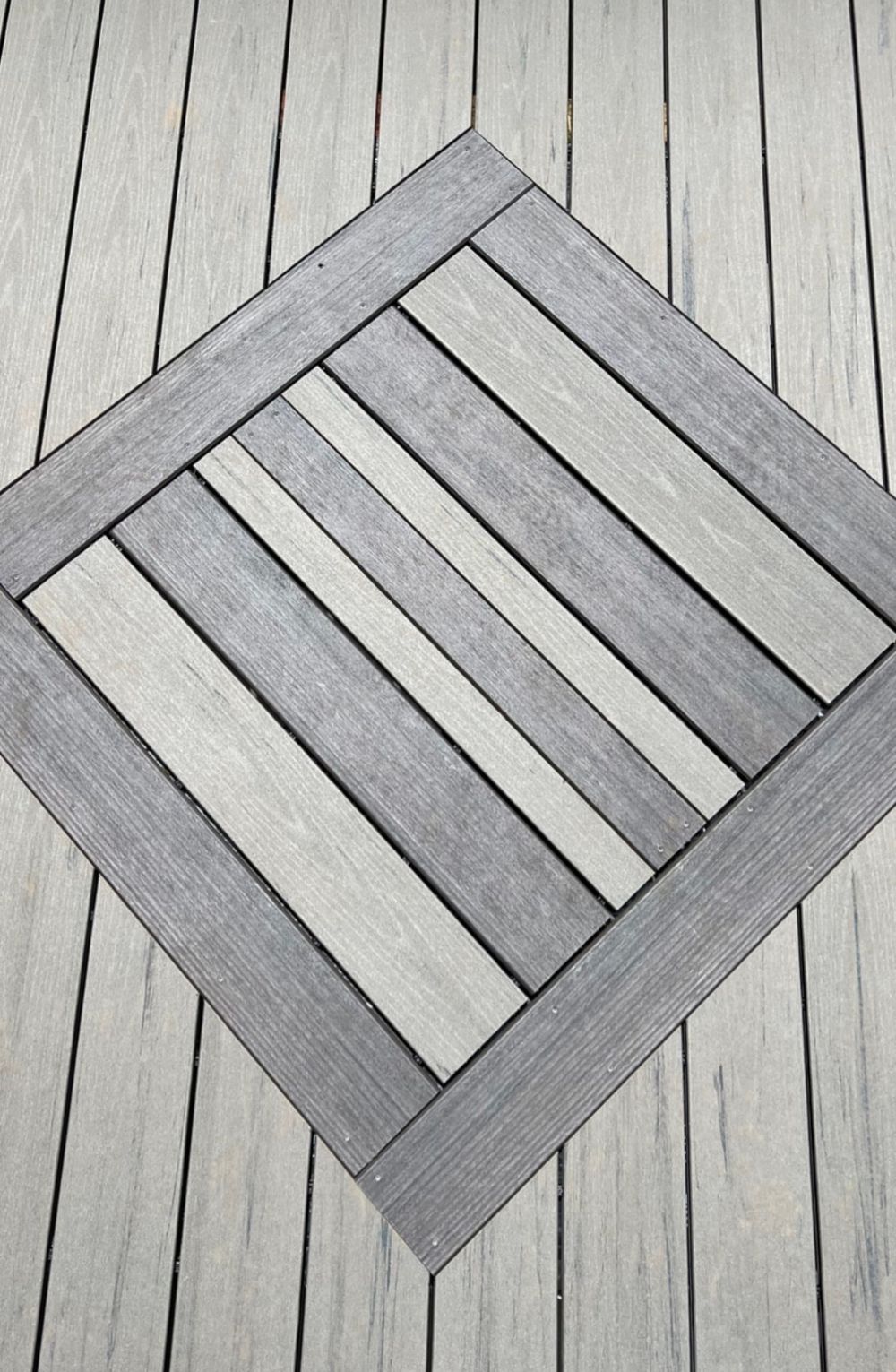 Geometric pattern of wooden deck boards arranged in diagonal lines creating a modern architectural detail.
