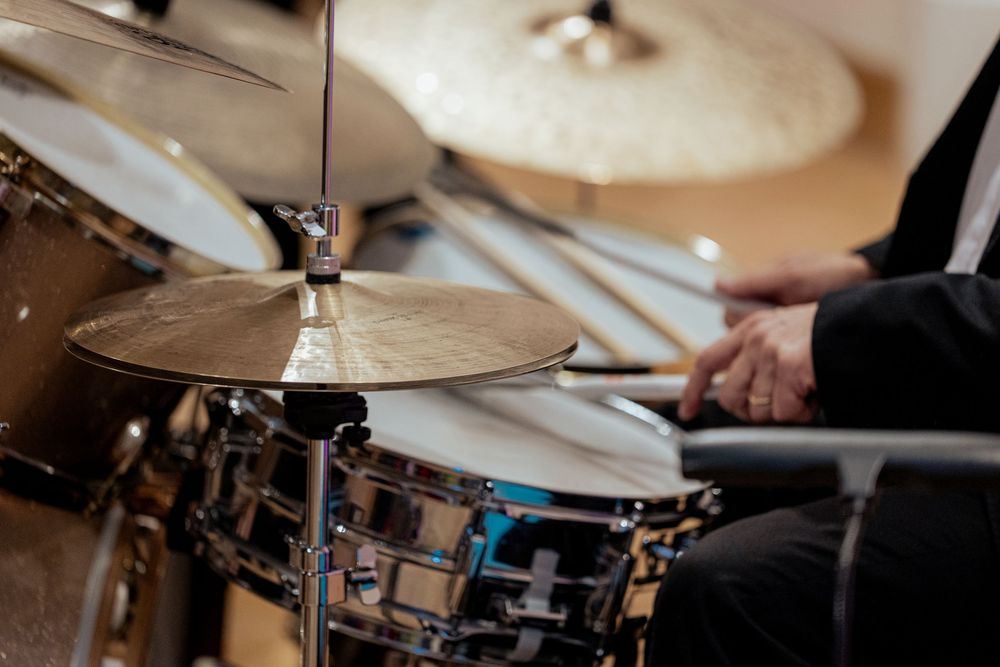 Close-up view of a drum kit with cymbals and hardware in warm lighting during a performance.