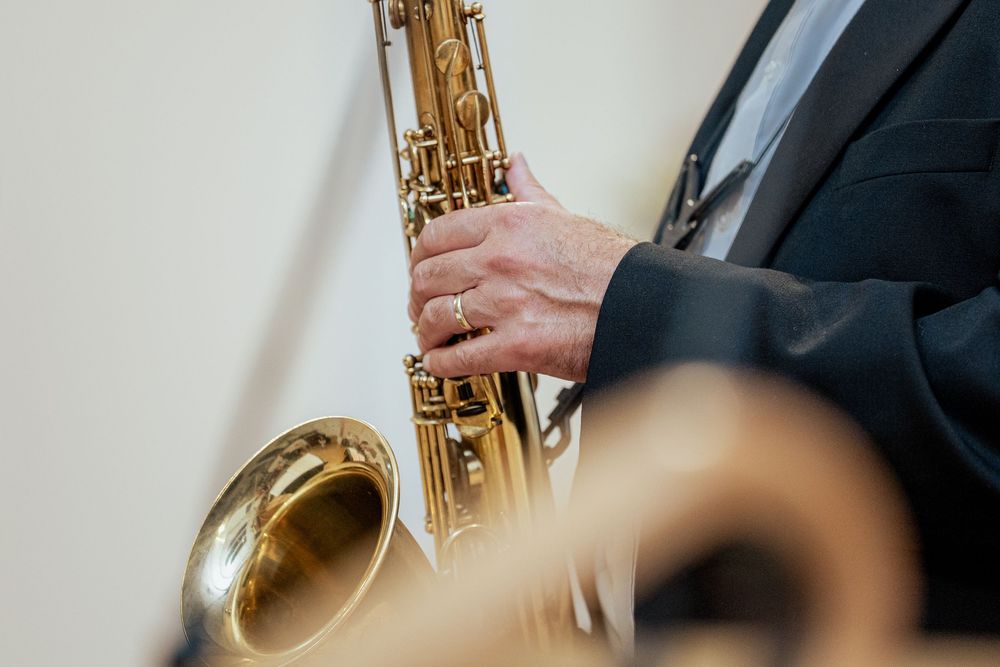 Close-up view of hands playing a brass saxophone with golden keys and valves in musical performance.