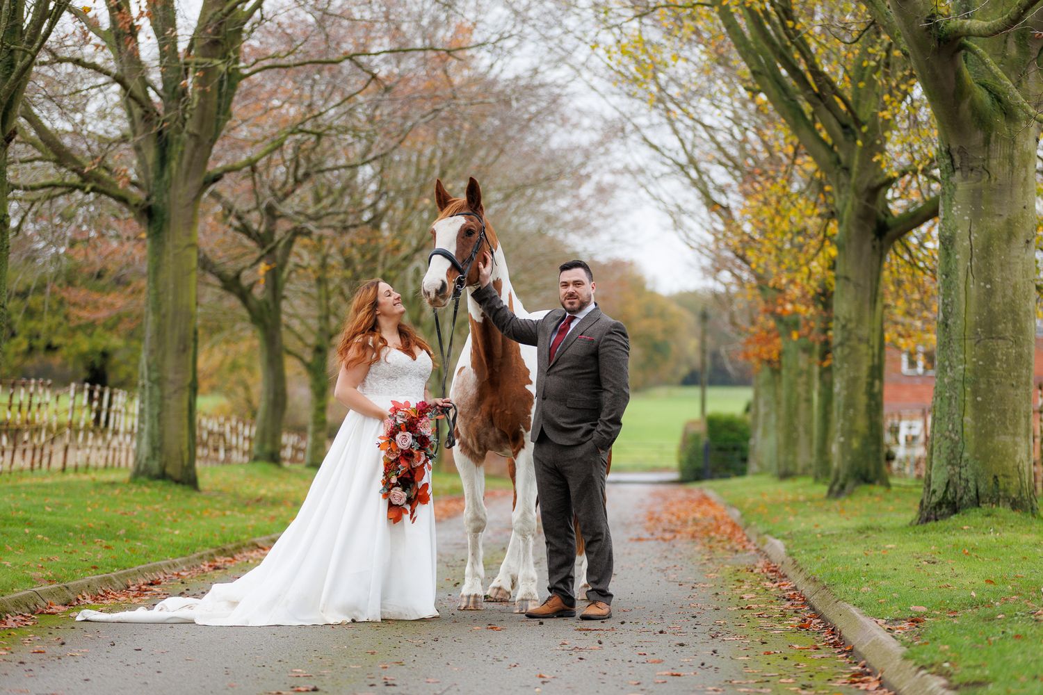 A beautiful black and white paint horse stands with a person on a sunny autumn day outdoors.