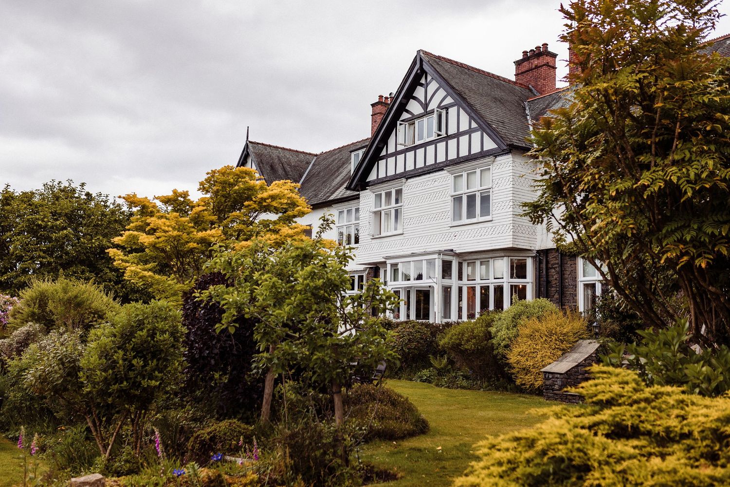 Scenic panoramic view of traditional Tudor-style homes nestled among autumn trees on a hillside residential street.