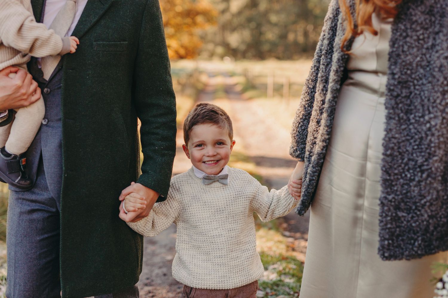 Autumn outdoor family photo session showing people walking and embracing among fall foliage and golden light.