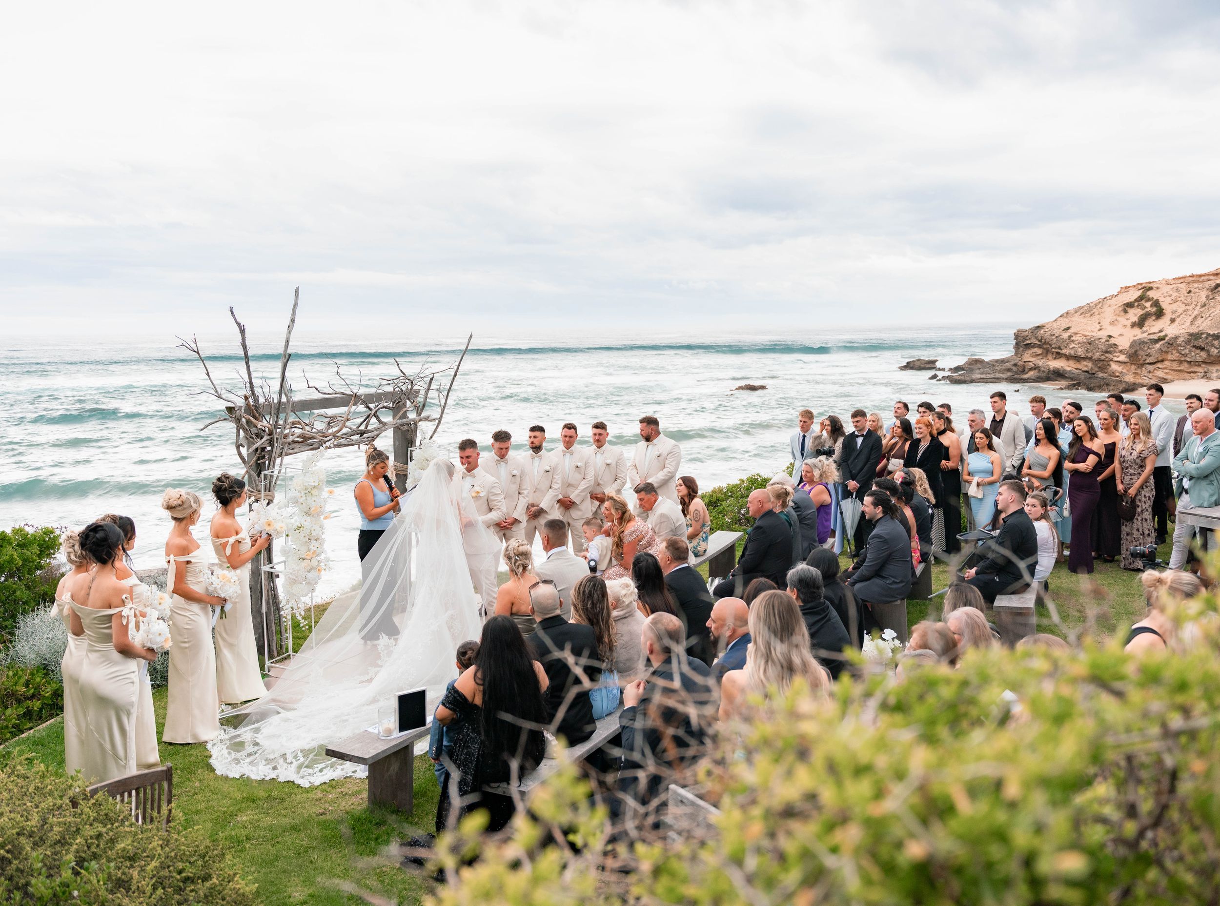 A collection of beach wedding ceremony photos showing guests gathered on a sandy shoreline with ocean waves in the background.