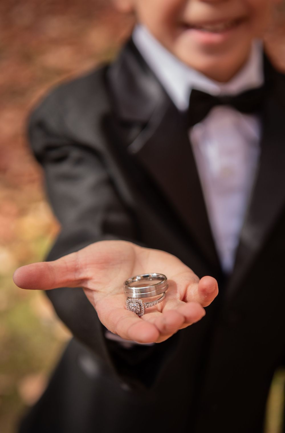 Wedding rings displayed in open palms against formal black attire.
