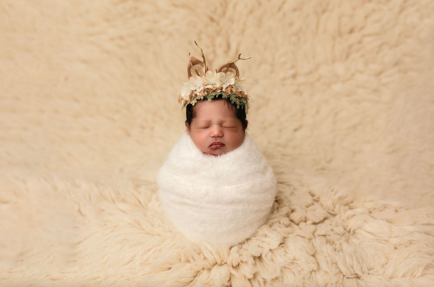 Newborn baby girl wrapped in cozy cream wool and wearing a reindeer hat sleeps in Charlottesville newborn photographer's studio.