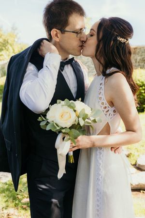 photo de couple mariage élégant le marié tient sa veste tout en embrassant son épouse dans les yvelines