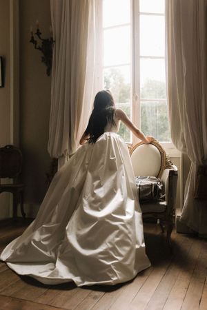 mariée regardant par la fenêtre d'un chateau pour son mariage