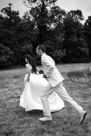 mariés courant à l'extérieur de leur lieu de réception pour leur mariage