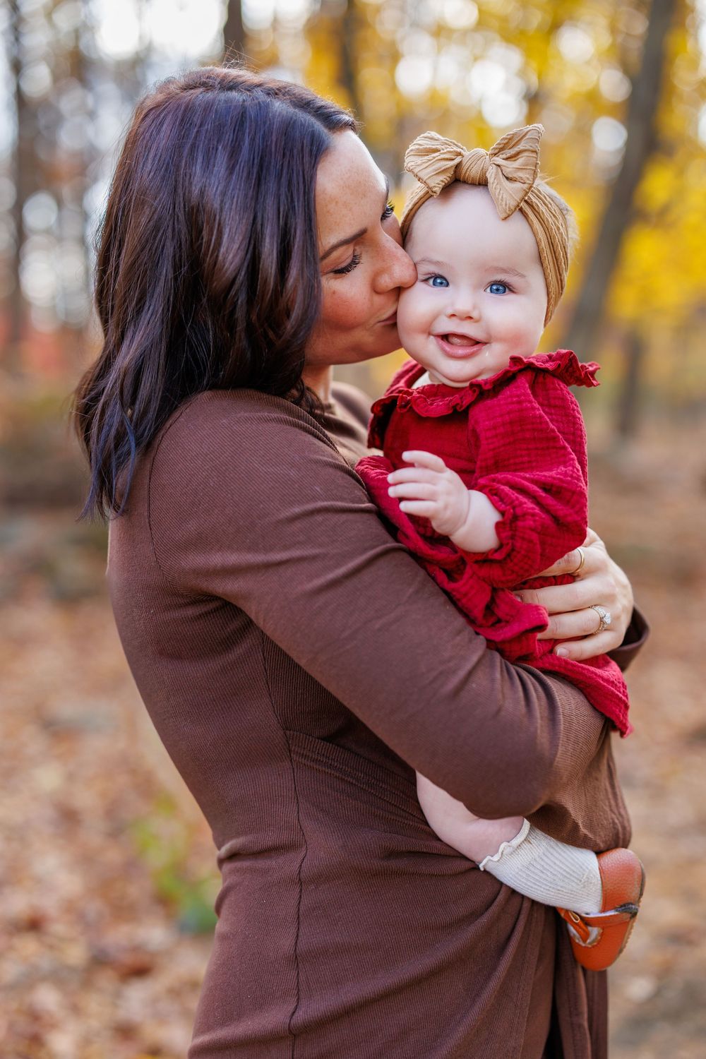 Tender moment captured in autumn forest setting with warm brown and red tones.
