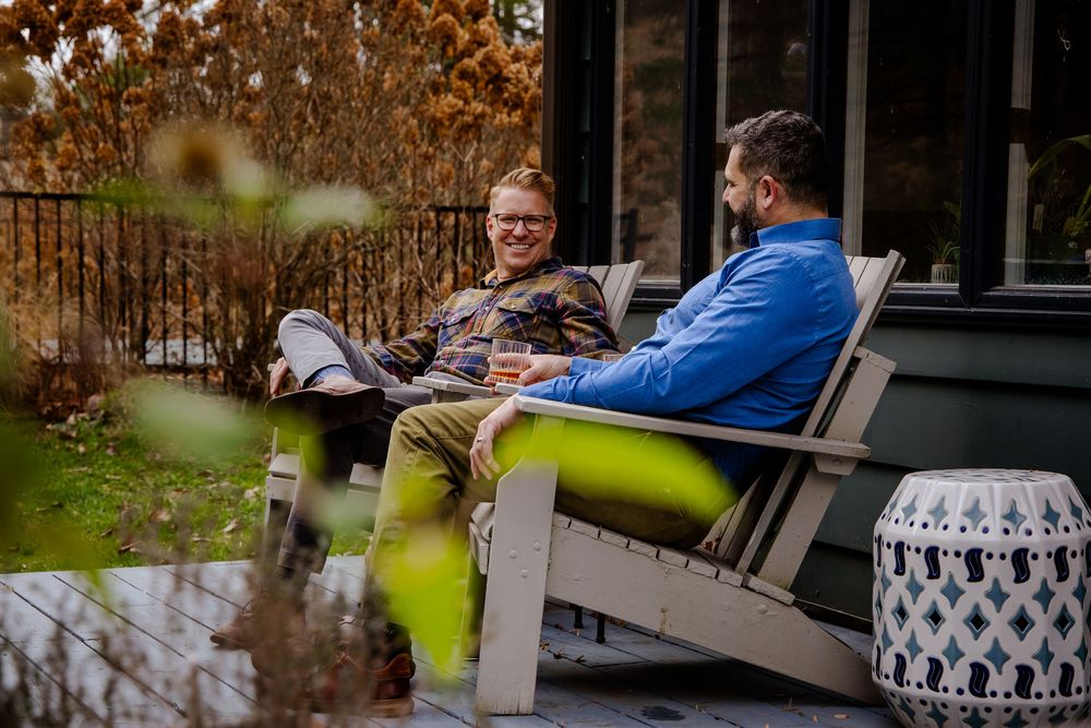 Husbands enjoying conversation while relaxing on outdoor patio furniture during autumn season.