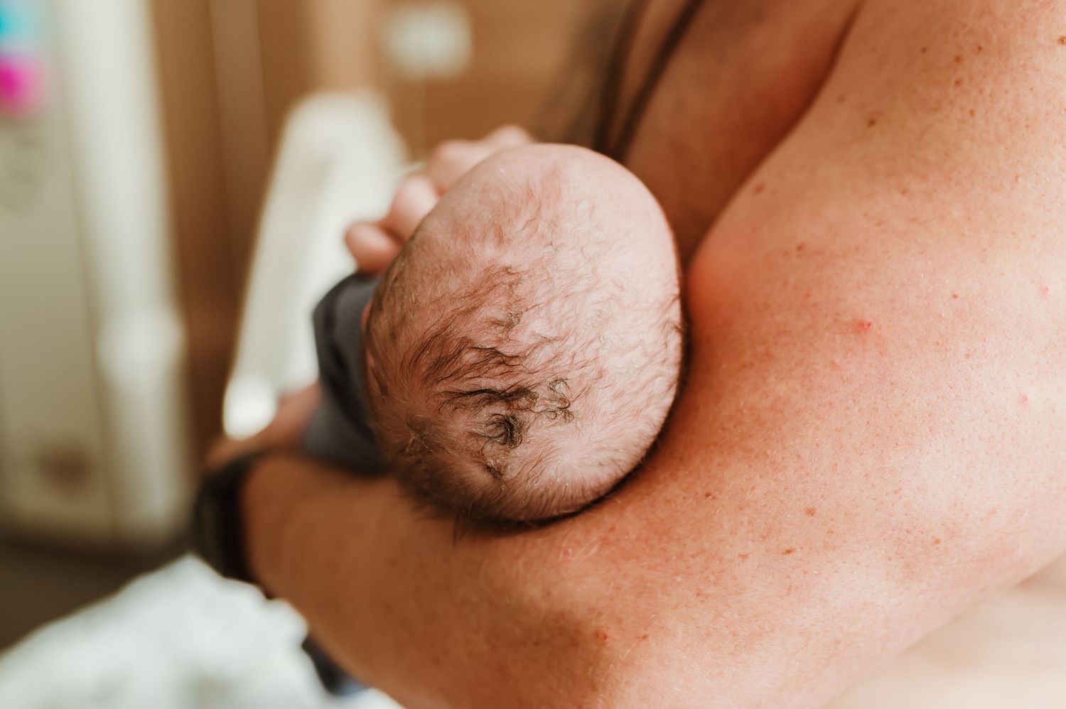 Close-up a newborn baby's head cradled in his fathers arms