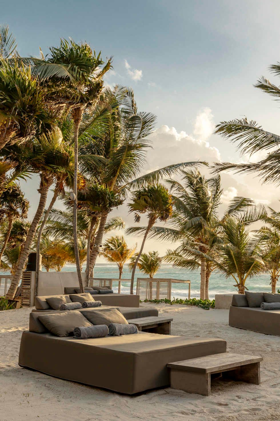 Luxury beach lounge chairs surrounded by palm trees at sunset with ocean view at tropical resort.
Casa Malca wedding photographer