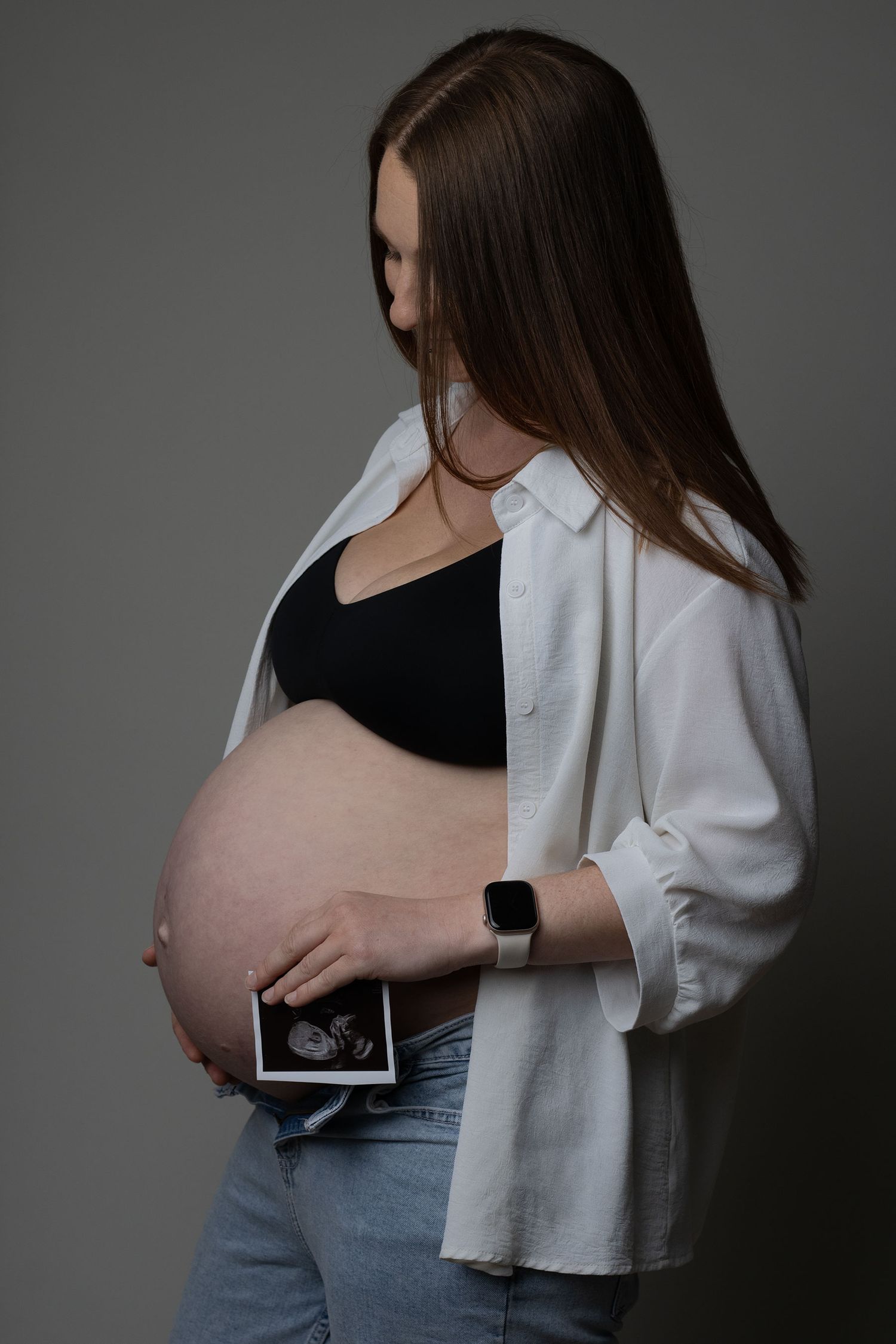 Pregnant mother holding baby scan image over her bump during a professional maternity session in Ceredigion