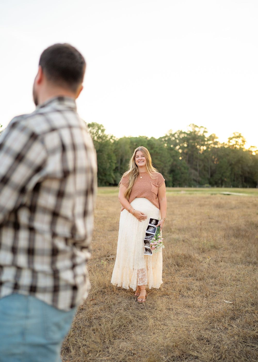 Pregnant mother posing with ultrasound picture during second baby announcement.