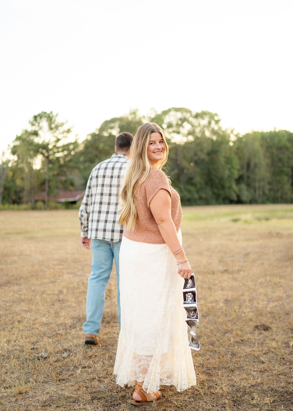 Candid moment of the Emersons walking hand-in-hand with their toddler during a maternity announcement session.