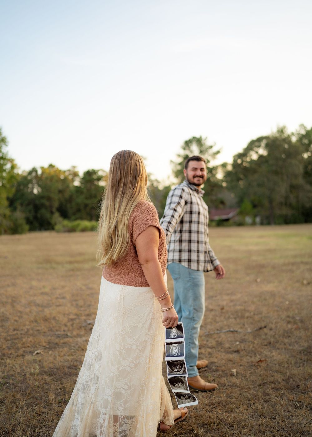 Candid moment of the Emersons walking hand-in-hand with their toddler during a maternity announcement session.