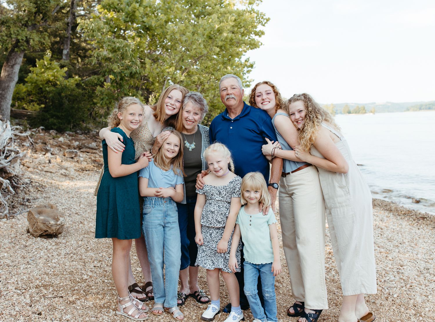 A family group poses together on a rocky beach shoreline during a casual outdoor photo session.