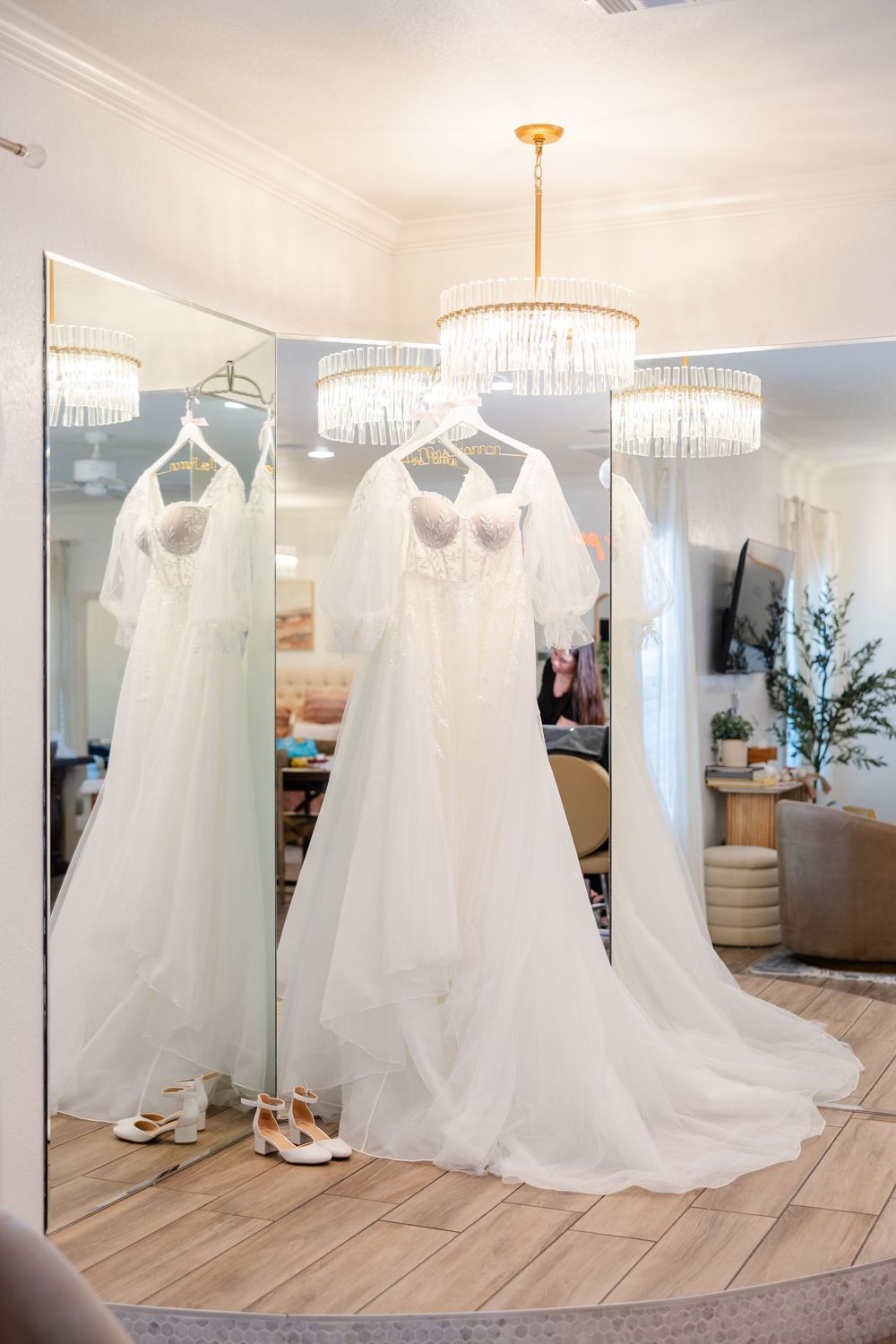 Elegant white wedding dresses displayed in a bridal boutique with crystal chandeliers and hardwood floors.