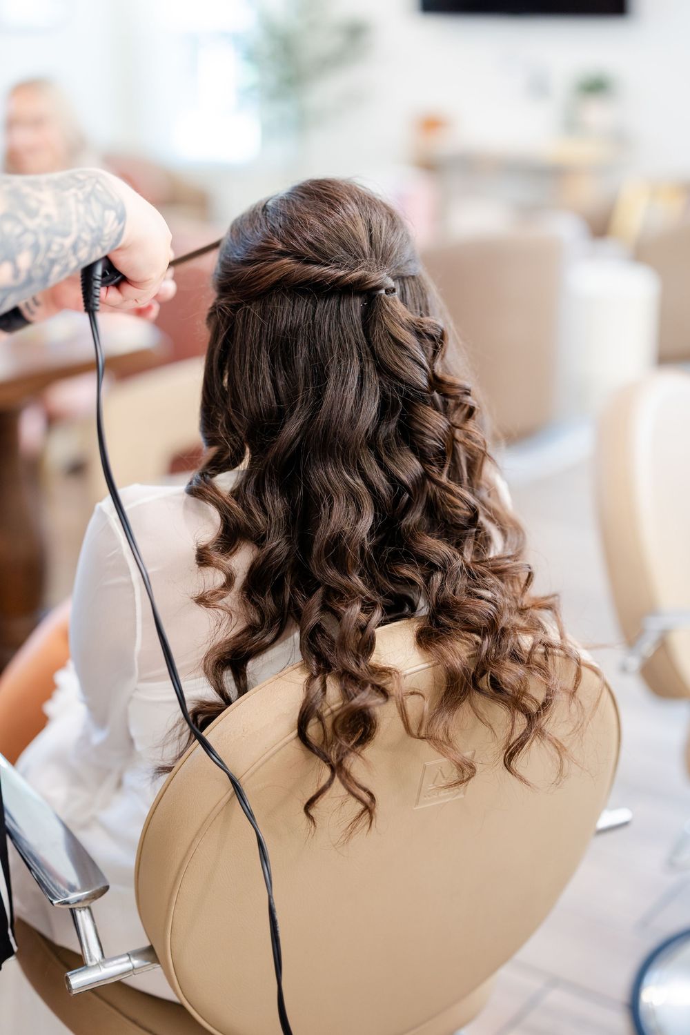 Close-up shots of curled brown hair being styled with a curling iron for a wedding preparation.
