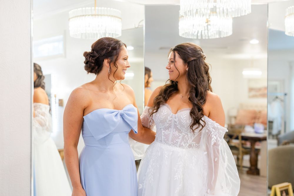 Two women in a bridal boutique share a joyful moment during a wedding dress fitting.