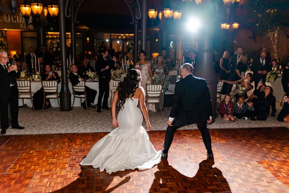 Wedding reception dance floor scene with elegant lighting and guests dancing in a grand ballroom setting.