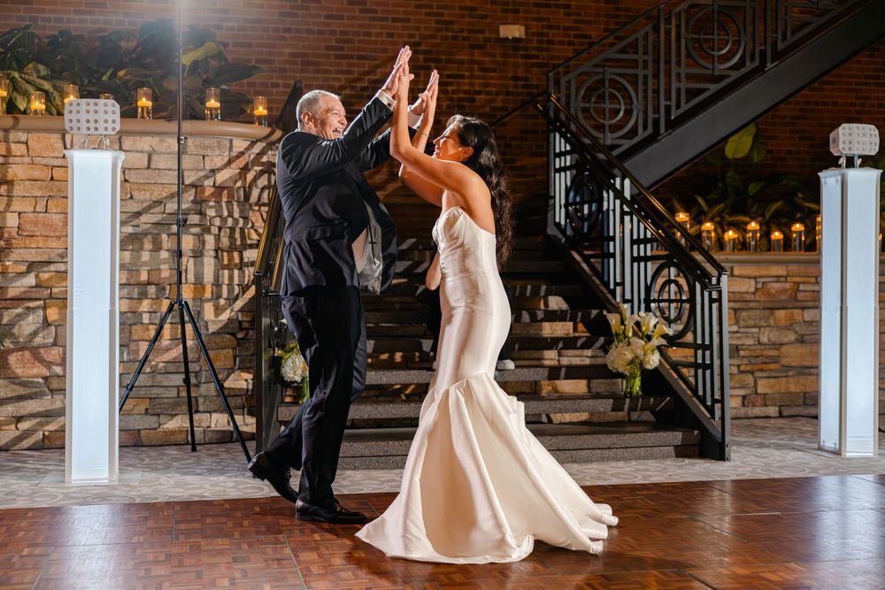 A couple dances together in a rustic venue with exposed brick walls and wooden floors.