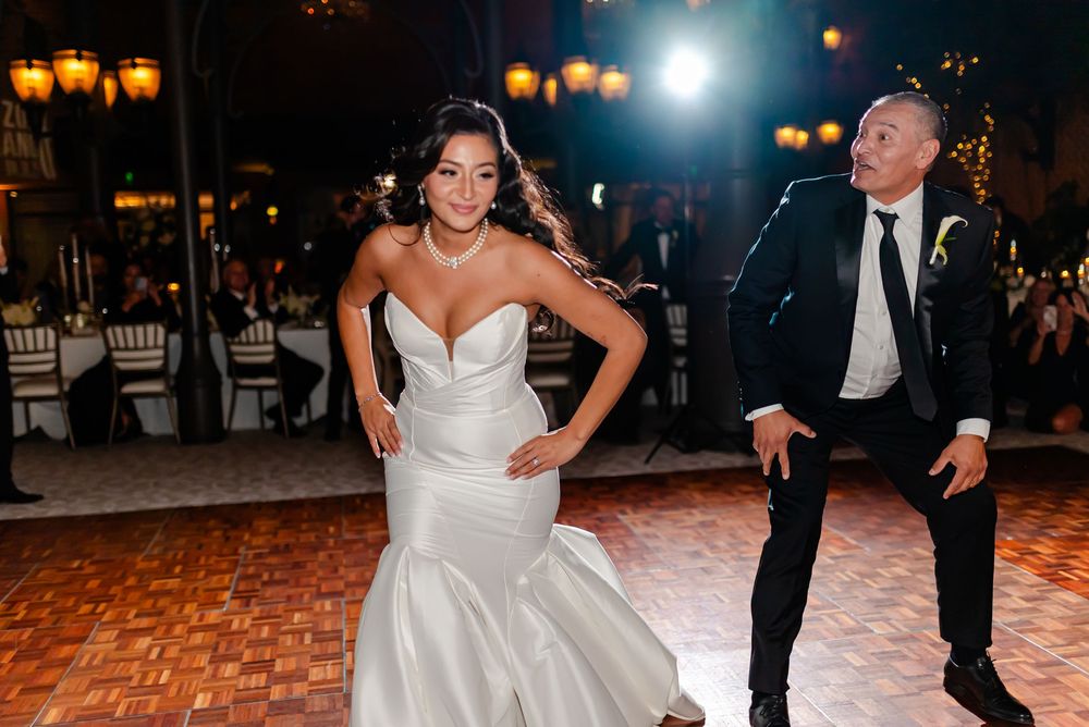 Wedding couple dances together at their reception with glowing lanterns illuminating the ballroom.