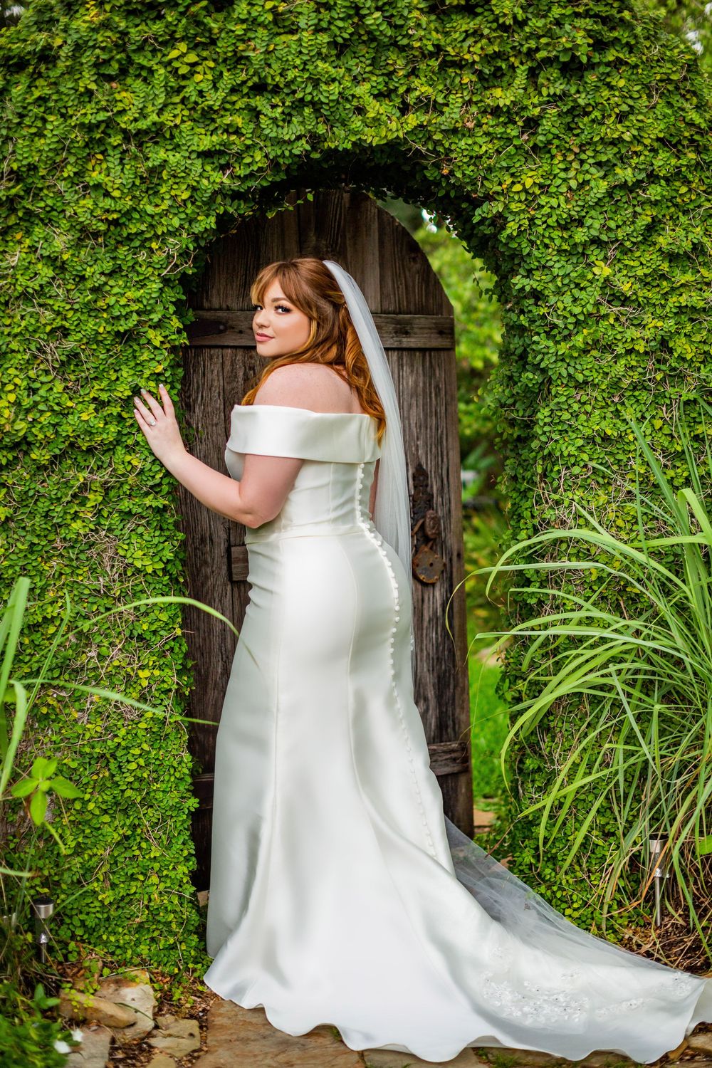 Classic white wedding gown with train photographed in a garden setting.