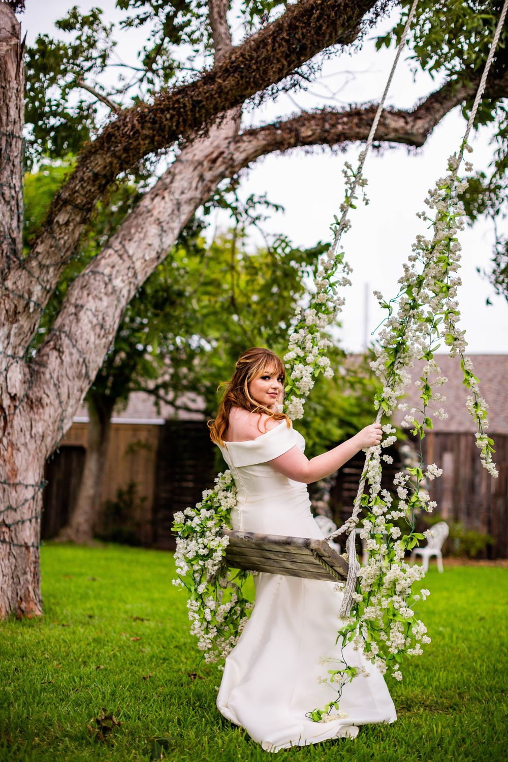 Whimsical bridal portrait with flowering tree branches in outdoor garden.