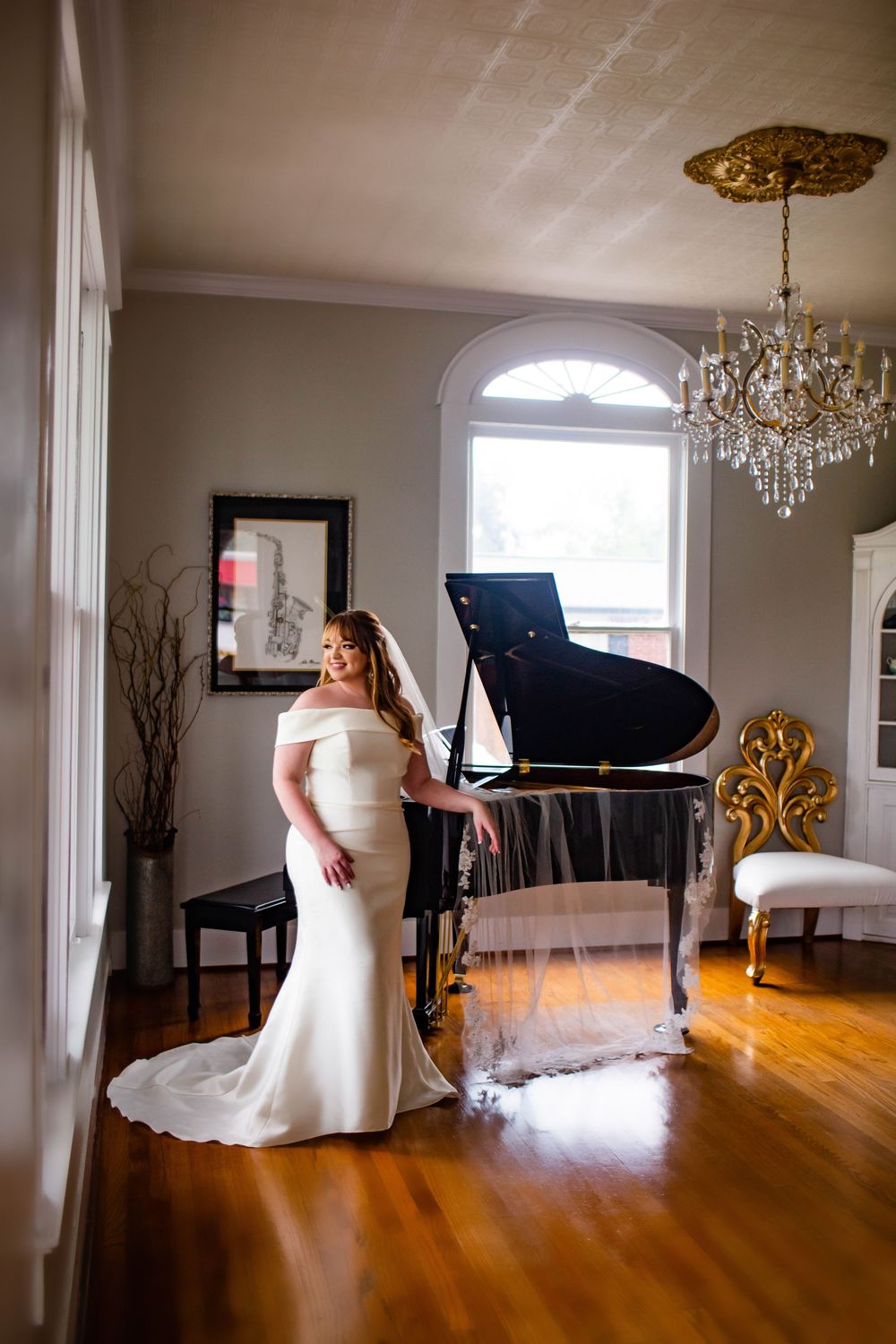 Wedding dress captured in panoramic view of room with piano and hardwood floors.