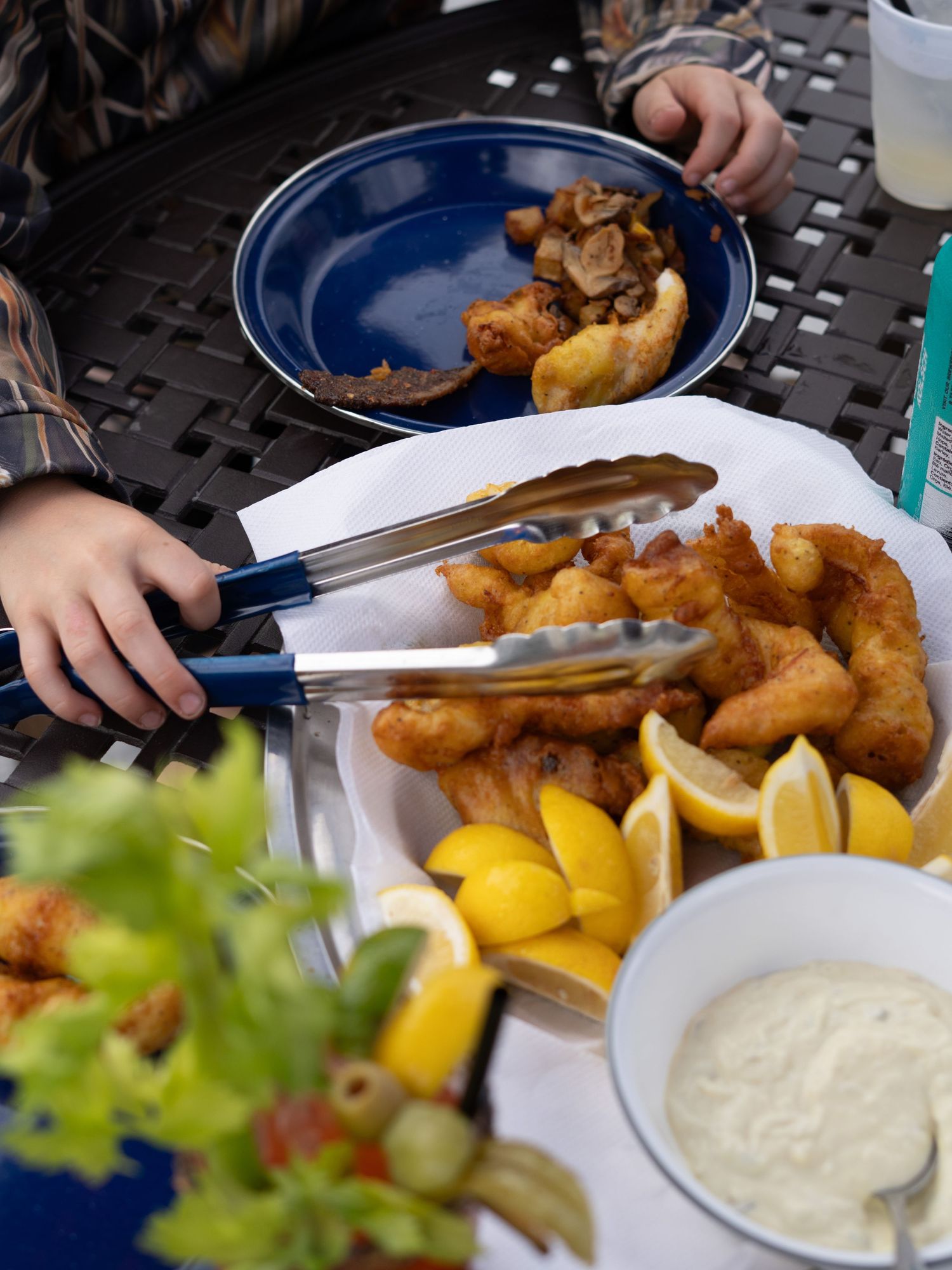Fried fish dinner served with lemon wedges and tartar sauce on blue plates.