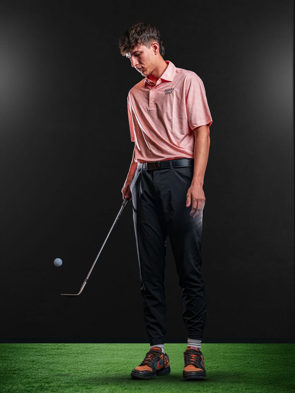 Dynamic Team Media Day Photo of golfer in pink polo shirt practices putting on artificial turf in studio setting - Warsaw, Indiana