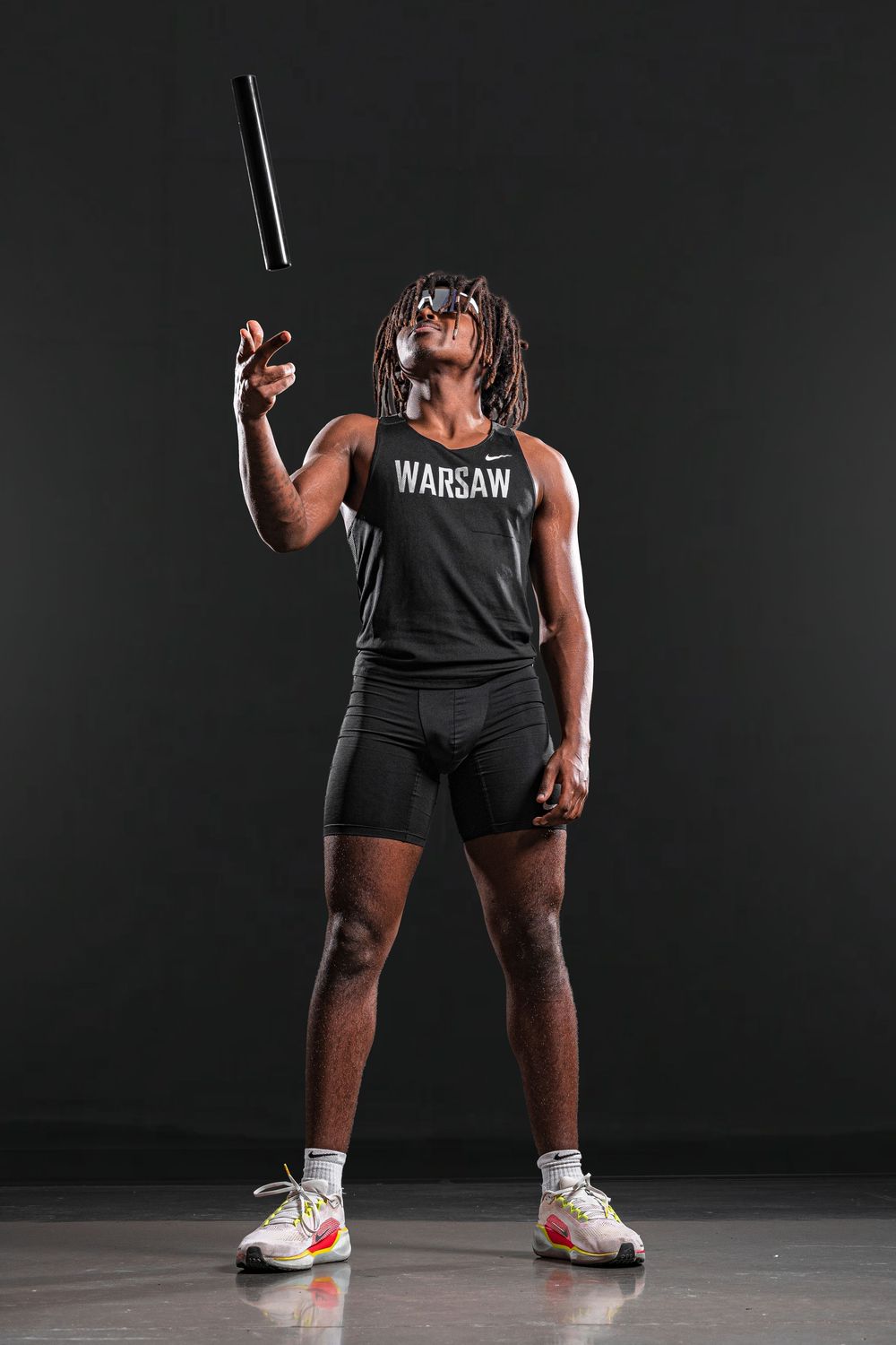 Team Media Day Photo of an athlete in Warsaw tank top throwing a baton against dark background - Warsaw, Indiana