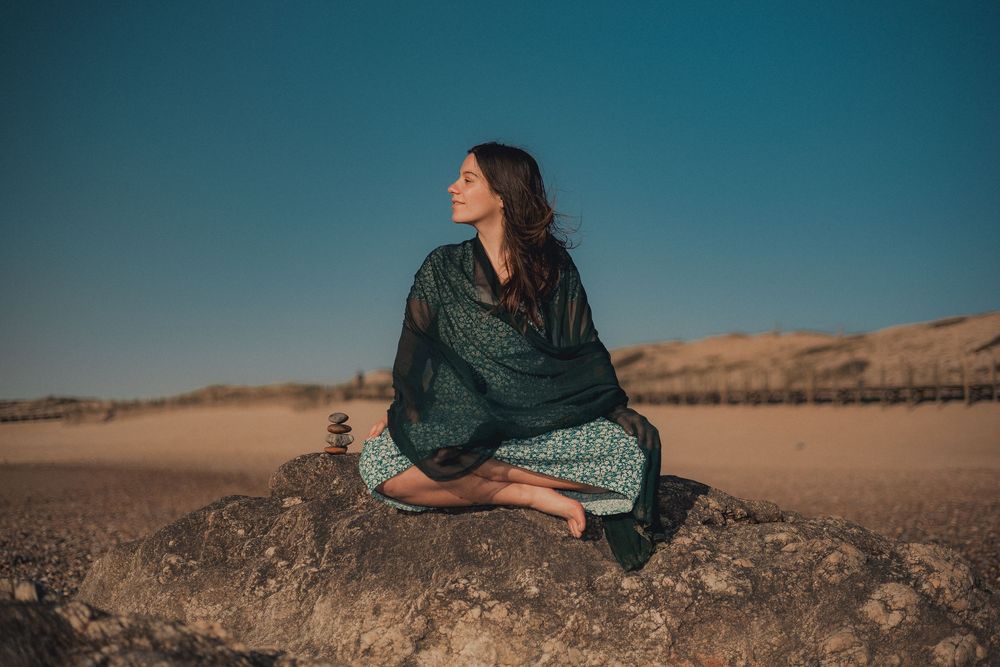Artistic portrait of someone reclining on desert rocks in flowing dress.