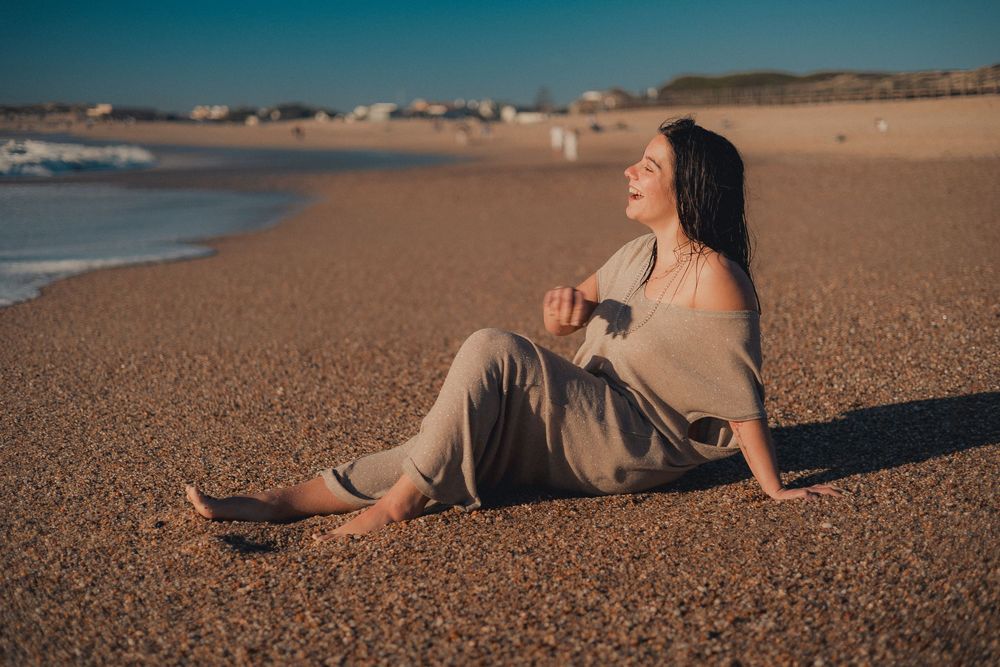 Figure lounges on sandy shoreline during golden hour.