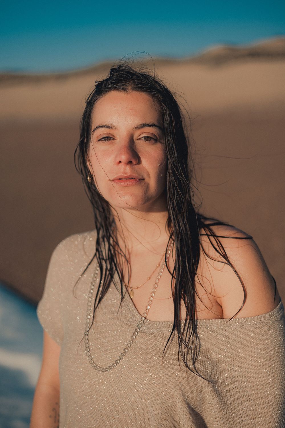 Sun-drenched beach portrait with wet hair and golden lighting.